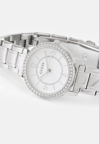 Silver wristwatch with a round case, white dial, Arabic numerals, and crystal accents around the bezel. Metal link bracelet, polished finish.