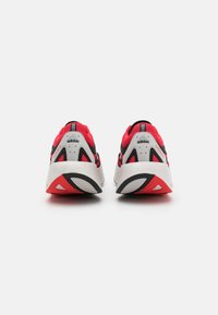 Červené a čierne športové topánky s vrchnou časťou z pleteniny, bielou podošvou a výnimočným dizajnom päty. Obsahujú branding Adidas a textúrované akcenty.