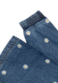 Pantaloni in denim con un tessuto blu decorato con margherite ricamate bianche e gialle sparse qua e là. Vita elasticizzata per una vestibilità e comfort ottimali.