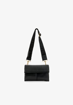 Black leather handbag with a textured top featuring pyramid studs. It has a detachable strap with the word "SAINTS" in black and gold hardware accents.