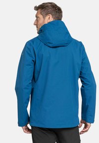 Chaqueta impermeable azul con capucha, con mangas largas y una textura suave. Costuras visibles y detalle del logo en la manga.