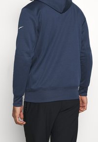 Felpa con cappuccio di colore blu navy realizzata in un tessuto morbido, con maniche lunghe, polsini a costine e un design semplice con dettagli delle cuciture.