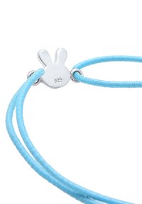 Silverfärgad kaninberlock med "925" märkning, fäst vid en dubbelsträng av ljusblå bomullssnöre, med en slät textur och enkel design.