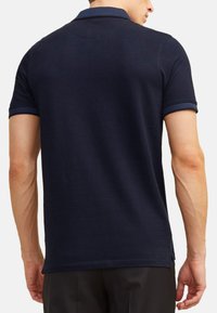 Marineblauw poloshirt met korte mouwen, voorzien van een geribde kraag en manchetten. Katoenmix stof met een soepele structuur. Getailleerde pasvorm.