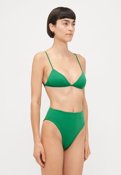 Zaļš bikini ar trīsstūrveida augšu un augstām biksēm, ar plānām siksnām un gludu, vienkāršu tekstūru. Vienkāršs dizains un spilgta krāsa.