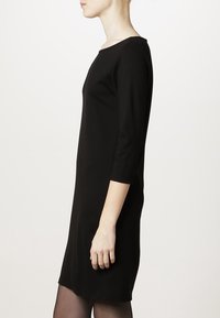 Robe noire midi avec des manches trois-quarts, col rond, texture lisse et silhouette ajustée.