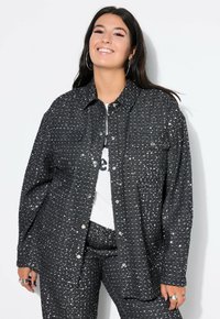 Schwarze, strukturierte Hemdjacke mit glänzenden Nieten, ausgestattet mit einem Kragen, Knopfverschluss und zwei vorderen Taschen.