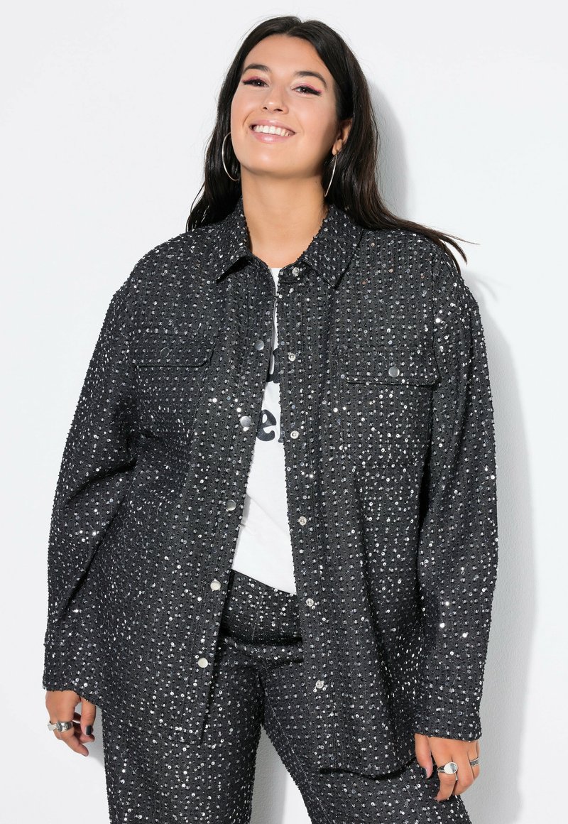 Schwarze, strukturierte Hemdjacke mit glänzenden Nieten, ausgestattet mit einem Kragen, Knopfverschluss und zwei vorderen Taschen.