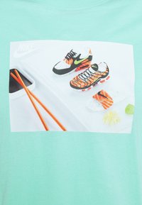 Mátově zelené tričko s živým potiskem tenisek, hůlek a sushi prvků. Tenisky jsou černé, oranžové a bílé s podrobnými vzory.