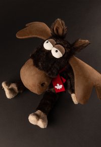 Plush moose toy with large brown antlers, big white eyes, cream-colored hooves, and a red scarf featuring a white maple leaf.