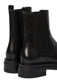 Bottines Chelsea en cuir noir avec des côtés élastiques, bout arrondi, tirettes et semelle en caoutchouc épaisse dotée d'un motif texturé pour une meilleure adhérence.