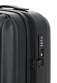 Czarna twarda walizka z teksturowaną powierzchnią, zamknięciem na zamek błyskawiczny i wbudowanym zamkiem szyfrowym dla zwiększenia bezpieczeństwa. Uchwyt jest gładki i solidny.