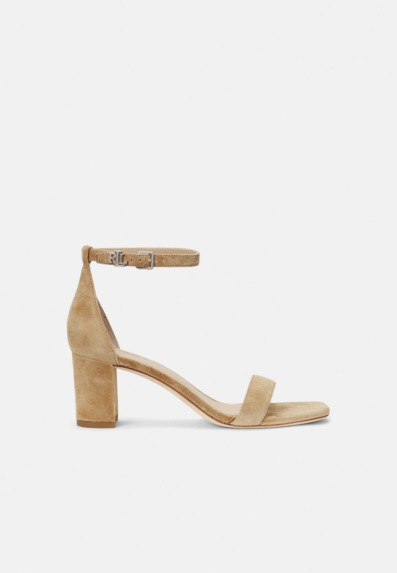 Beige suède blockhak sandaal met een enkele teengreep, enkelband met gespsluiting en een gladde textuur.