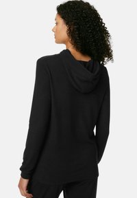 Svart hoodie i ett mjukt material, med en enkel design, långa ärmar och en rund, justerbar huva bak.