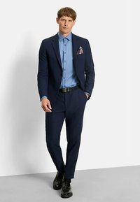 Navy suit with a tailored fit, light blue shirt, patterned pocket square, and sleek black shoes. Smooth fabric and structured design.