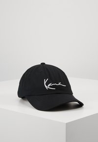 Svart baseballkeps i bomull med krökt skärm. Har en vit broderad logotyp på framsidan. Stängd justerbar rem på baksidan.