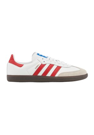 Weißer Adidas Samba Sneaker mit roten Streifen, rotem Fersenlasche, beiger Zehenkappe und brauner Sohle, seitlich gezeigt.
