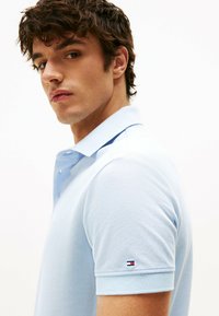 Polo shirt azzurro chiaro realizzato in tessuto testurizzato, con colletto classico e maniche corte, dotato di un piccolo logo del brand sul polsino sinistro.