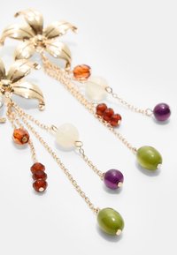 Ohrringe in Goldoptik mit floralem Blätterdesign, versehen mit hängenden Edelsteinperlen in Bernstein, Lila, Grün und Klar, an zarten Ketten.
