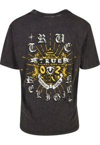 Juodas medvilninis marškinėliai su dideliu grafiniu dizainu, akcentuotu geltonomis spalvomis, kuriame yra užrašai "True Religion" ir "World Tour" skirtingais šriftais.