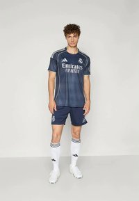 Tengerészkék focimez fehér részletekkel, a "Emirates Fly Better" felirattal, passzoló sorttal és csíkozott zoknikkal. Az adidas márkajelzés látható.