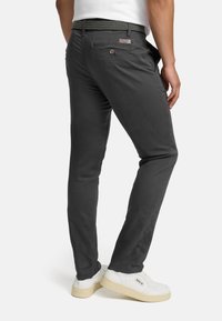 Grijze slim-fit broek met een gladde textuur, voorzien van een tailleband met een patroonriem, details aan de achterzak, gecombineerd met witte sneakers.