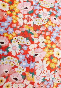 Floral-patterned fabric in red, featuring pink, blue, and yellow flowers. Includes buttons in bright red, with visible stitching details.