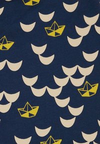 Tessuto blu navy con un motivo ripetitivo di barche di carta gialle e forme di onde bianche. Il design presenta accenti geometrici nelle barche.