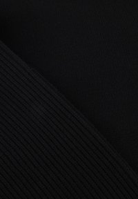 Tessuto a maglia nero con un lato liscio e un'altra superficie a coste, che presenta una palette di colori monocromatica e un materiale morbido.