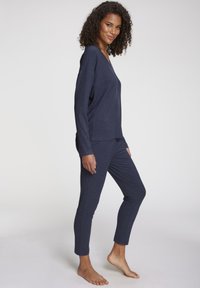 Navy blue, ribbed loungewear set featuring a long-sleeve top and tapered pants, showcasing a relaxed fit and soft texture.