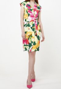 Kukkakuosisessa mekossa on keltaista, vaaleanpunaista ja vihreää, vyötäröllä vyö, hihattomat hihat ja napit edessä. Vaaleanpunaiset korkokengät.