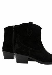 Botines de ante negros con tacón bajo, que cuentan con una cremallera lateral y una asa. Textura suave con detalles de costura y punta redondeada.