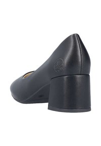 Zapato de mujer de piel negra, con tacón medio y punta redonda, con logo grabado cerca del tacón, visto desde un ángulo trasero.