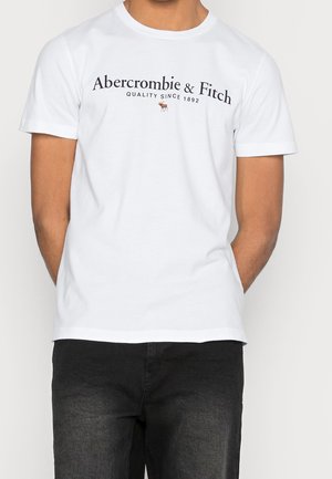 Biała bawełniana koszulka z krótkimi rękawami, z czarnym napisem "Abercrombie & Fitch" i małym logo. Prosty dekolt typu crew neck.