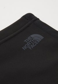 Sort stof med The North Face-logoet trykt nær den stiknede kant.