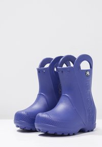 Botas de lluvia de goma moradas con suela texturizada, puntera redondeada y dos asas de tiro. Presenta un logotipo en el costado y detalles estriados en el talón.