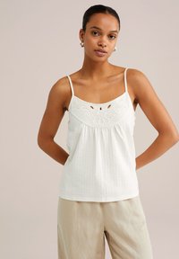 White tank top with a textured fabric, featuring embroidered floral details, adjustable straps, and a flared silhouette.