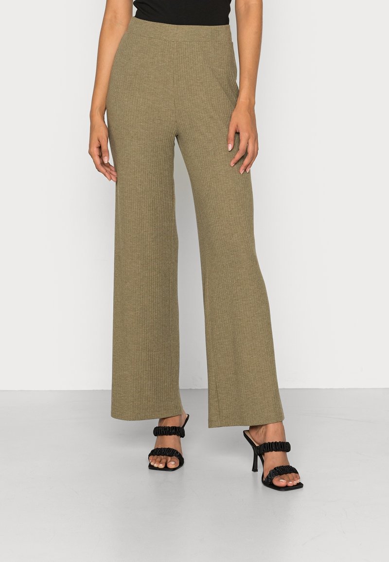 Pantalons larges côtelés olive en tissu doux, dotés d'une taille haute et associés à des talons noirs à lanières.