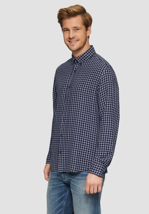 Marineblauwe geblokte button-up shirt van geweven stof; voorzien van een gespreide kraag en lange mouwen, gecombineerd met lichtblauwe spijkerbroek.