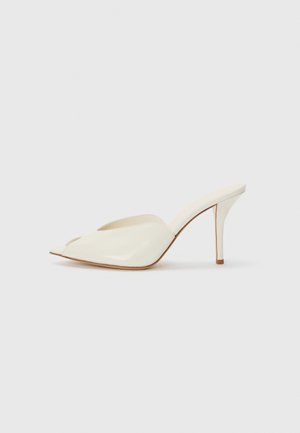White patent leather open-toe mules with a pointed design, slender high heel, and smooth texture; minimalist style with subtle stitching details.