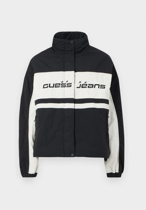 Juodai baltas pūkinis švarkas su aukštu kaklu, horizontaliomis juostelėmis ir "Guess Jeans" logotipu ant krūtinės, elastingomis rankovėmis ir priekinių kišenių.