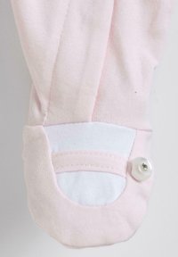 Cuff in cotone rosa chiaro con rivestimento interno bianco, caratterizzato da una forma arrotondata e un accento decorativo con bottone lucido.