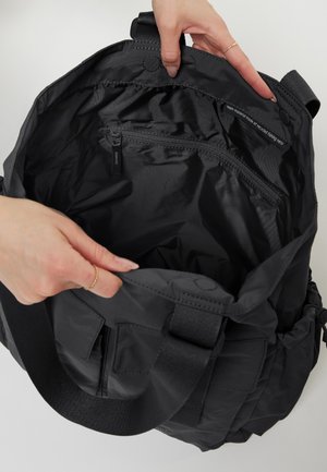 Borsa tote nera con una texture liscia e opaca. Presenta una tasca interna con zip e spallacci robusti e regolabili. L'interno è spazioso e privo di fodera.