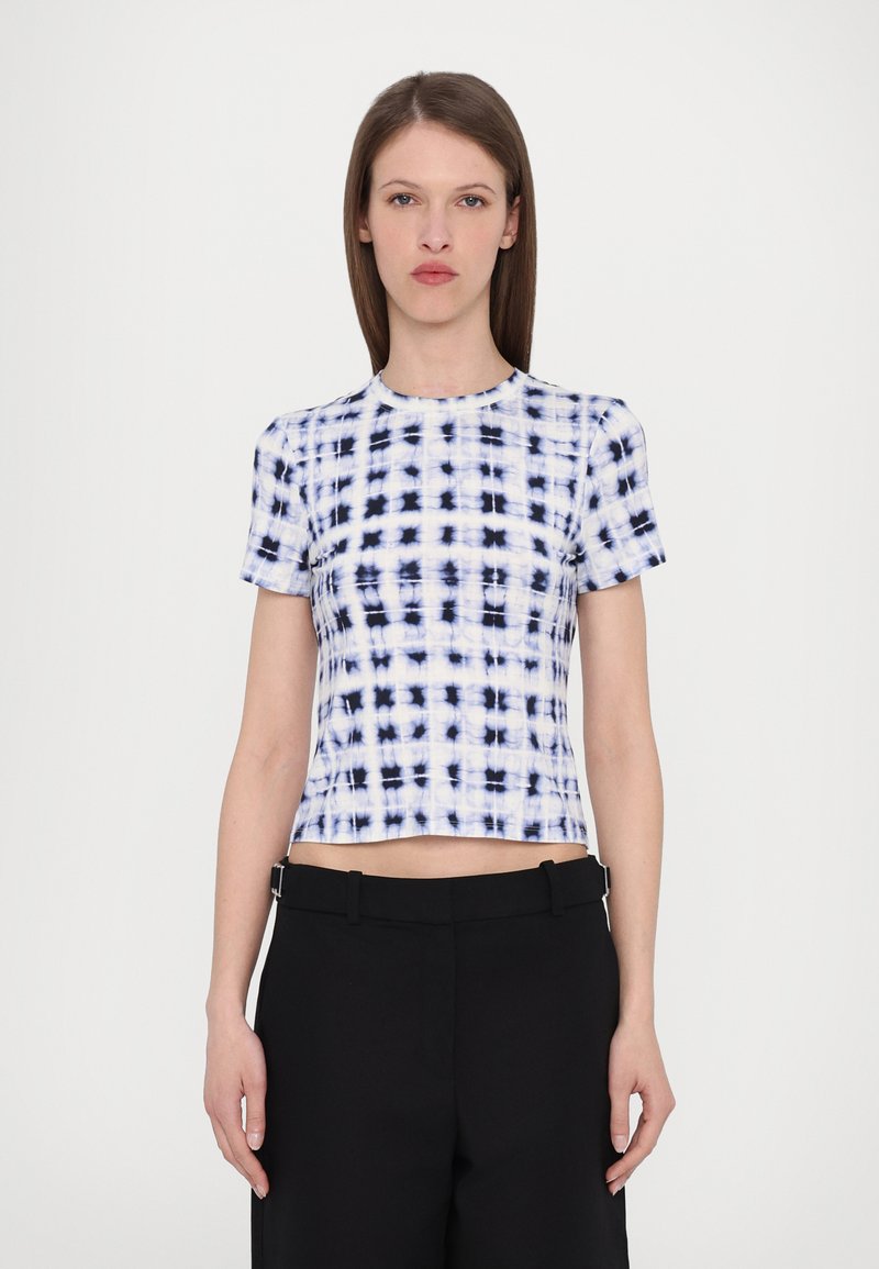 Kortermet crop top i hvit og marineblå tie-dye mønster. Laget av jevnt stoff med rund hals og tettsittende design. Kombineres med svarte bukser.