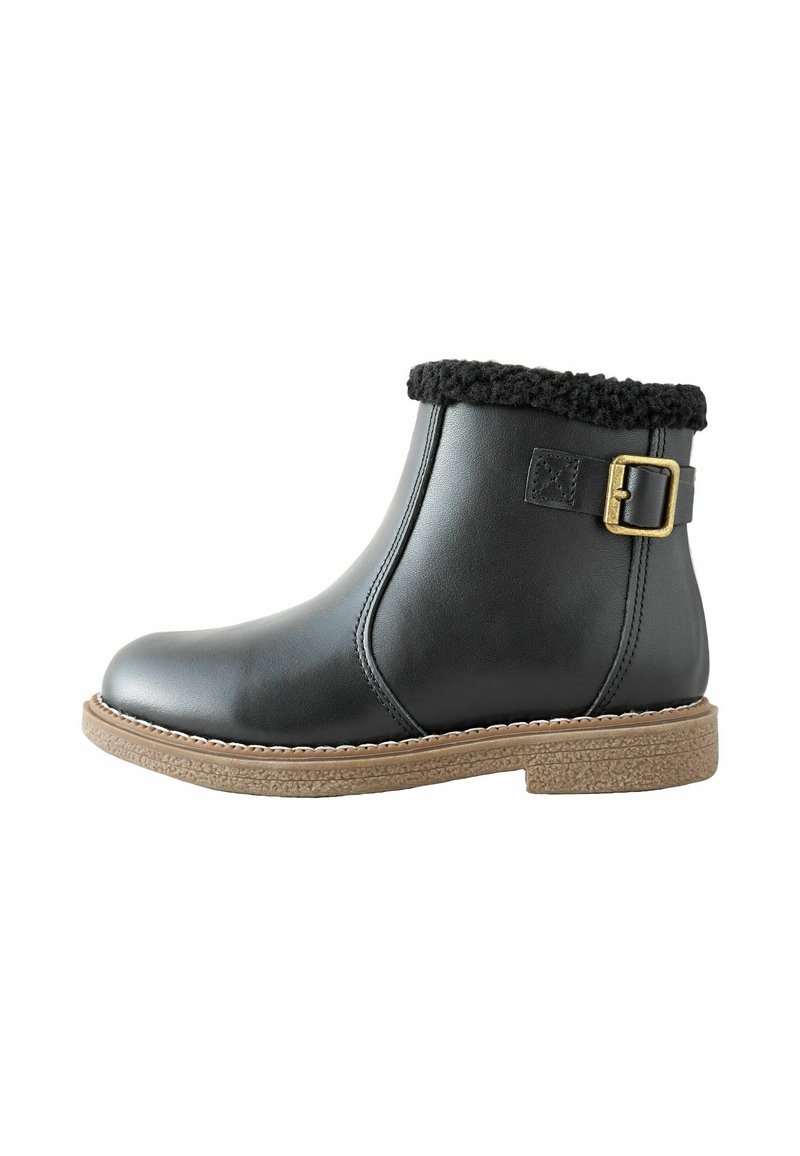 Schwarze Leder-Ankle-Boots mit einem Kragen aus Kunstfell, seitlichem Schnallenverschluss und einer strukturierten, braunen Sohle. Glatte Oberfläche mit minimalen Steppnähten.