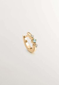 Pendiente de aro dorado con tres piedras preciosas: una azul y dos claras. Superficie lisa con acabado pulido, forma curva y cierre seguro.