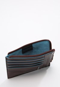 Billetera de cuero marrón con acentos azules, cierre de cremallera, múltiples ranuras para tarjetas y protección RFID. Forro interior suave en azul contrastante.