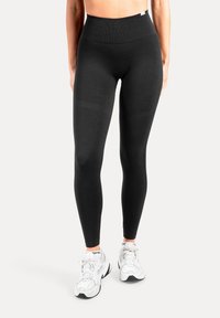 Schwarze Leggings mit hoher Taille aus dehnbarem, glattem Stoff. Verfügen über einen breiten Bund und eine eng anliegende Silhouette.