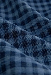 Navy blue checked fabric with a textured surface, featuring dark and light blue squares in a diagonal pattern and a soft, woven appearance.