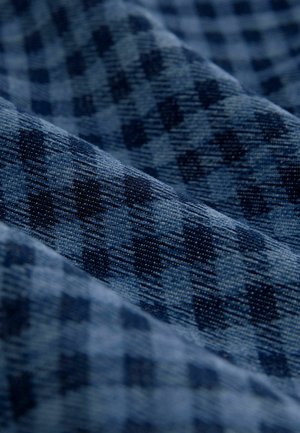 Tessuto a quadri blu navy con superficie textured, caratterizzato da quadrati blu scuro e chiaro disposti in un motivo diagonale e un aspetto morbido e tessuto.